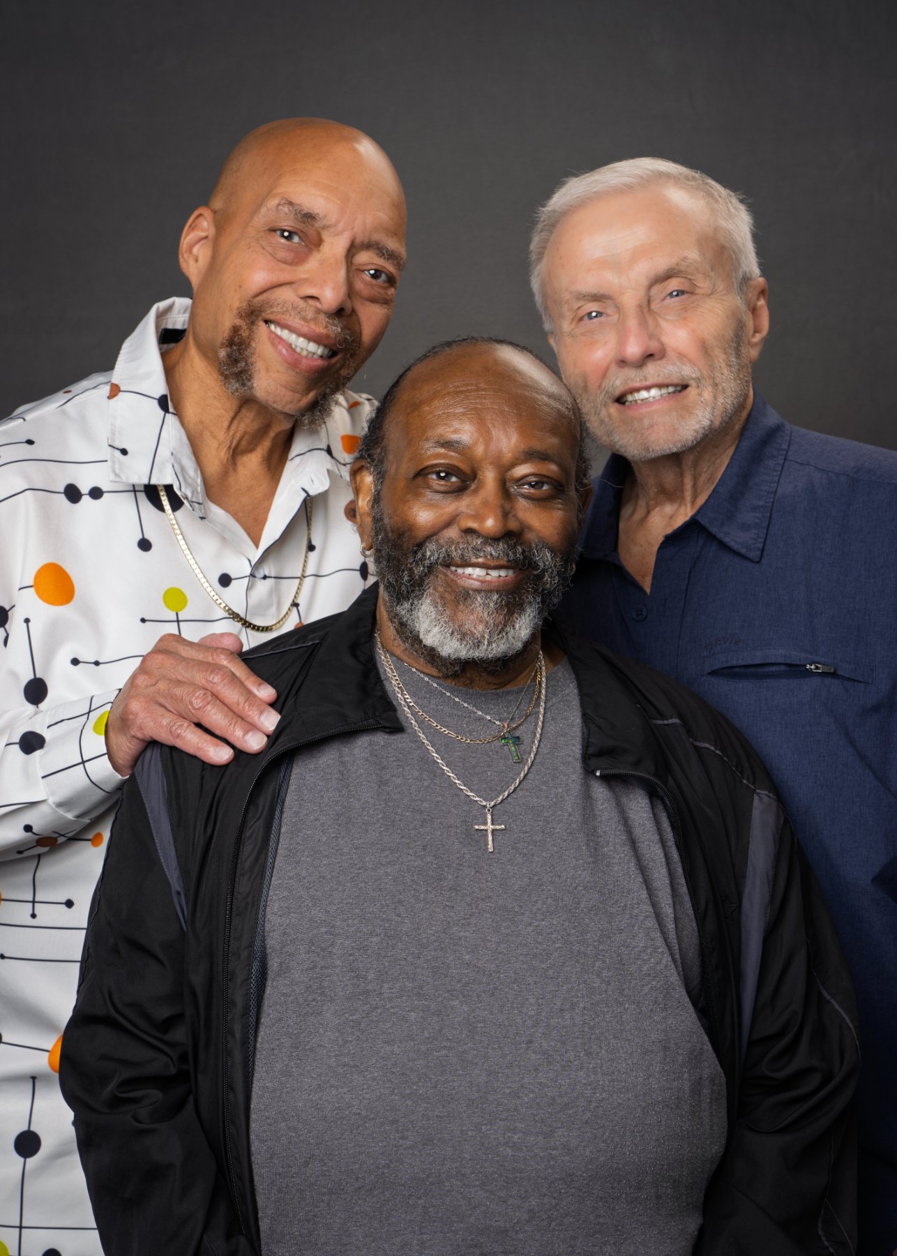 Three older adults standing close together and smiling